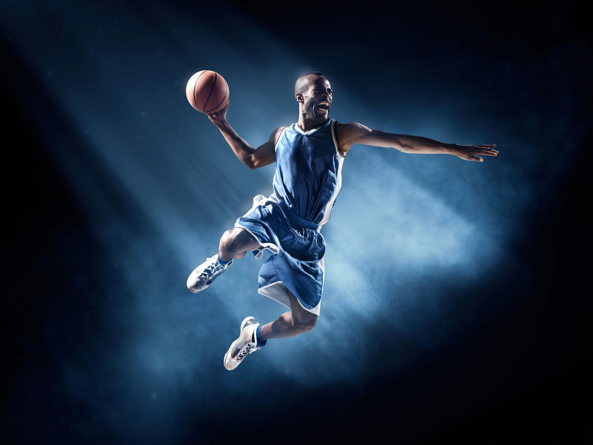 Basketball player rising for a shot under arena lights